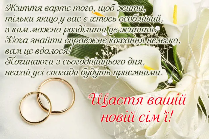 Білі квіти та золоті кільця на весільному привітанні.