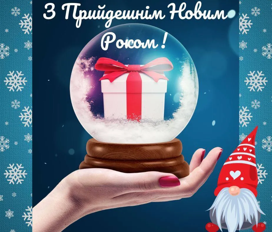 Рука тримає снігову кулю з подарунком та привітанням на новий рік.