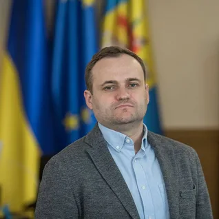 Портрет Олексія Кулеби на фоні прапорів України та ЄС.
