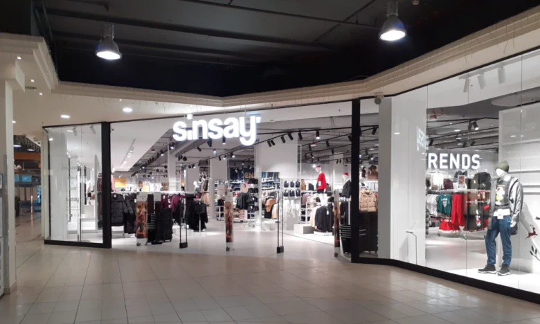 Вхід до магазину одягу бренду Sinsay з освітленою назвою.