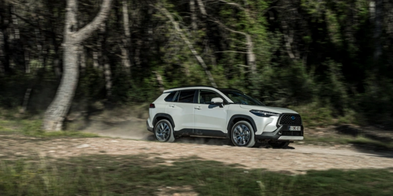 Білий автомобіль Тойота їде по лісовій дорозьці