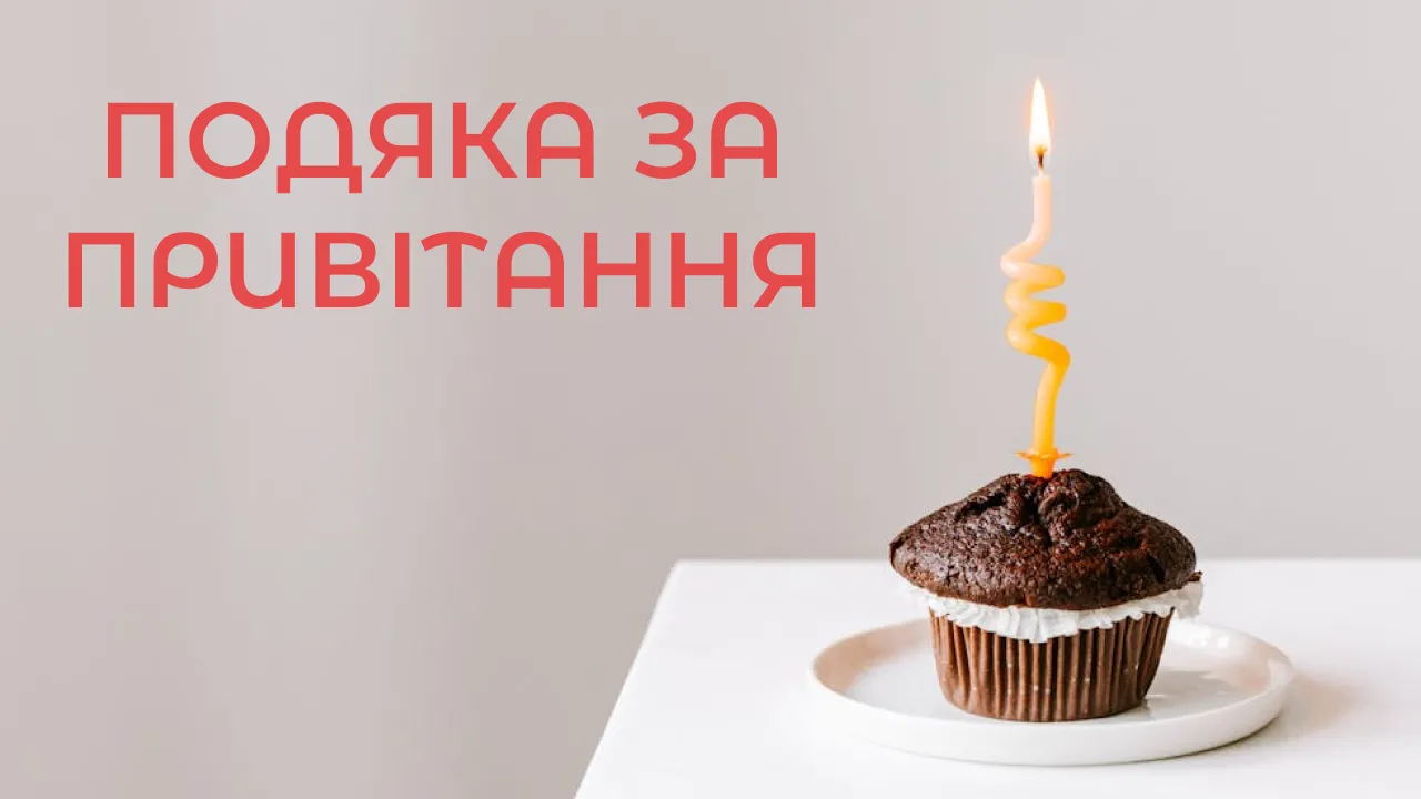 Шоколадний кекс із запаленою свічкою на білій тарілці.