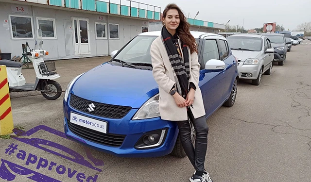 Жінка поруч із синім вживаним автомобілем від Motor Scout.