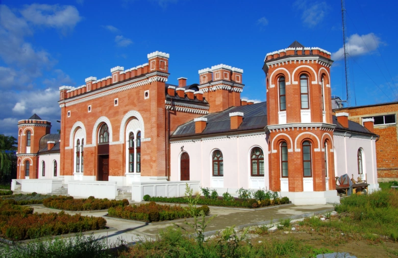 Історична цегляна будівля в парку під блакитним небом